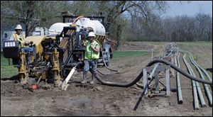 Savoy Energy LP workers install a pipeline in a farm field off  Howell Highway in Adrian. City com­mis­sion­ers signed con­tracts with the firm for oil leases of more than 1,100 acres of city-owned land.