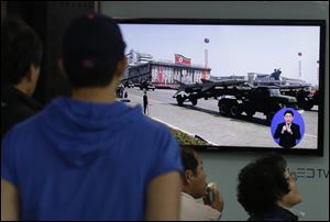 South Koreans watch TV news showing a footage of North Korean missiles on a military parade, at a Seoul Train Station in Seoul, South Korea