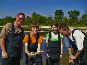 Alex Kocher (Bowsher) holds a longnose gar that he and fellow Wildlife Management students Will Gilbert III (Waite), left, Leigha Kelley (Waite), and Tres' Black (Start) netted during field work on the Maumee River.