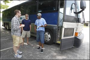 From left: Lifeline volunteer Bryce Roberts, intern Rob Anderson and volunteer Gary Bond converse prior to boarding this bus that will take them from New Harvest Church in Oregon to Monroe, Ohio, where soccer players will kick a soccer ball to Toledo as part of a charity fundraiser.