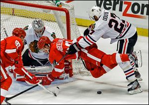 Chicago’s Johnny Oduya checks Detroit’s Justin Abdelkader in front of goaltender Corey Crawford in Monday night’s game.