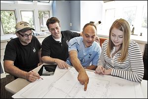 Tim Brandvold, left, and Scot Waggoner show plans for a kitchen remodel to Chris and Jen Romans in Minneapolis. Experts advise homeowners to be sure contractors are licensed to do the job.