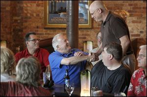 Peter Cavanaugh, center, greets Mark Benson during a dinner and reunion of local radio broad-casters at Manhattan’s Restaurant in the Uptown district. Mr. Cavanaugh, a member of the Rock and Roll Hall of Fame and former Toledo radio broadcasting exec, put together the reunion.