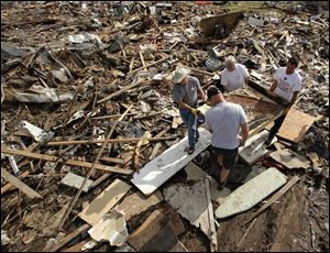 Friends and family members carry what remains of piano through the rubble at a tornado-ravaged home, in Moore, Okla.,  Saturday.