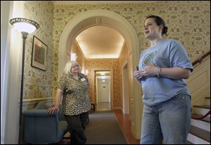 Employees Susan Roberts-McGlade, left, and Angela Metcalf, right, talk about the house during a tour. Originally known as Stranleigh Manor, the mansion was once the estate of Page and Robert Stranahan.