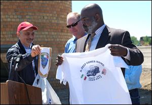 Vittorio Argento, left, presents Toledo-Lucas County Port Authority president Paul Toth, center, and Toledo Mayor Mike Bell with gifts after he brought an original Willys MB (Jee) from Italy back to the Willys-Overland factory site in Toledo.