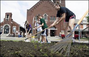 Mary Kate Guidici, 16, of Orland Park, Ill., right, joins other volunteers to till a patch of land on Tuesday in preparation for flowers at Helping Hands of St. Louis Outreach Center.