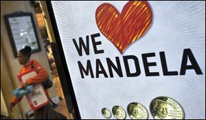 A shopper walks past a sign advertising a shop that sells commemorative coins with the face of Nelson Mandela in the Sandton City shopping centre in Johannesburg, South Africa.