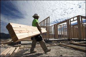 Construction worker Miguel Fonseca carries lumber as he works on building a house in Chula Vista, Calif. Framing lumber now costs 67 percent more than it did at its low price point in 2009.