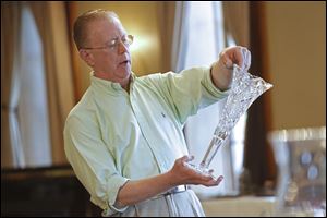 Insured Professional Antique Appraiser Richard Stegman discusses the value of a hand-cut Libbey Glass vase as he offers appraisals on objects brought by local residents to the DeGage Jazz Cafe during the Maumee Valley Historical Society fund-raiser.