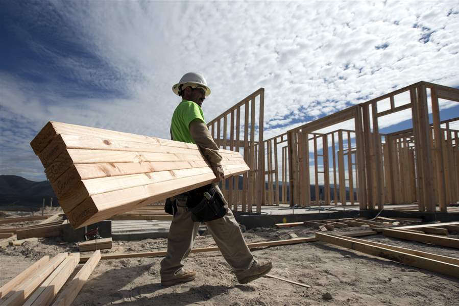 Construction-worker-Miguel-Fonseca-carries-lumber-as-he