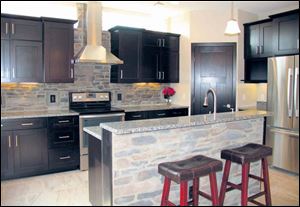 Stainless steel appliances and stone look great against the kitchen’s dark cabinets. The door at right opens to a large pantry.