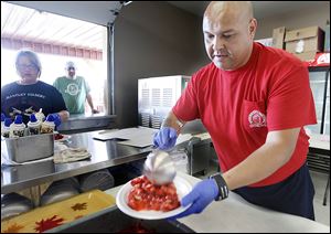 Jason Obregon makes strawberry shortcake during the 75th annual Holland Strawberry Festival at the Community Homecoming Park. Most of the fund-raiser’s proceeds go to a children’s charity.