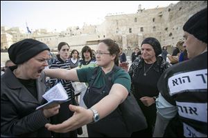 An Israeli member of the Women of the Wall organization, right, tries to hug an ultra-Orthodox woman as they pray at the Western Wall.