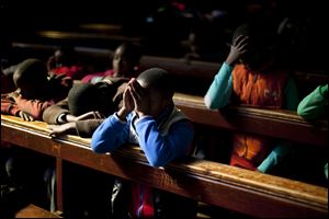 School children pray in the Regina Mundi church in Soweto township on the outskirt of  Johannesburg, South Africa, Sunday June 16, 2013.  Former South African president Nelson Mandela remained hospitalized for the ninth day with an occurring lung infection.