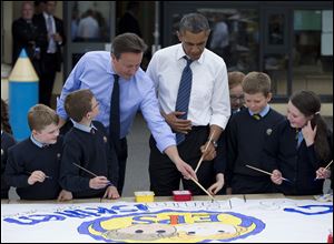 President Obama and British Prime Minister David Cameron help students paint a mural during a visit to the Enniskillen Integrated Primary School in Enniskillen, Northern Ireland, today.