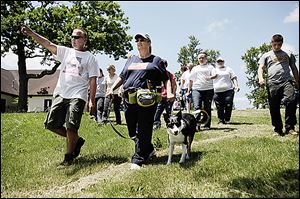 Tracy Finley of Toledo points as he walks with Ft. Wayne, Ind,. resident Gale St. John and her trained cadaver dog, Simon, at Navarre Park. The group searched the park Wednesday for Elaina Steinfurth.