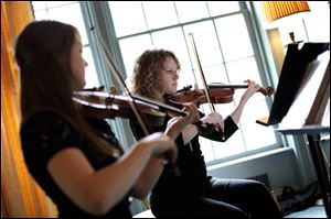 Toledo School for the Arts student Arianna Dyer of Ottawa Hills, right, plays the violin along with student Olivia Bryan of Sylvania during the first ‘Noon Tunes’ on Friday at the Wildwood Preserve Metropark Manor House in Toledo.