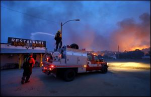 Firefighters spray water on a restaurant to help protect it from flames in the Glenn Ilah area Sunday near Yarnell, Ariz. An Arizona fire chief says the wildfire that killed 19 members of his crew near the town was moving fast and fueled by hot, dry conditions. The fire started with a lightning strike on Friday and spread to 2,000 acres on Sunday amid triple-digit temperatures.