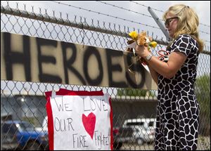 Maggie Greenwood adds flowers to a makeshift memorial at the fire station Monday, in Prescott, Ariz., where an elite team of firefighters was based. Nineteen of the 20 members of the team were killed Sunday when a wildfire suddenly swept toward them in Yarnell, Ariz.