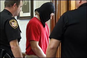 Michael Aaron Fay, his face obscured, is escorted from Juvenile Court after a hearing on Tuesday. He is accused in the deaths of Blaine and Blake Romes, who were 14 and 17, respectively.