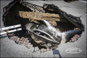 A sinkhole on North Detroit Avenue near Bancroft Street swallowed a car and its driver. Pamela Knox, who was taken to a hospital for examination, was not injured. Officials said a water main had burst as well. 