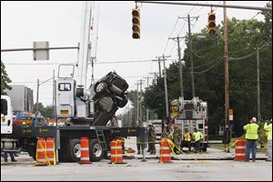 A Chevy Malibu is pulled from a sink hole that caved in near an old water main at the corner of Bancroft Street and Detroit Avenue.