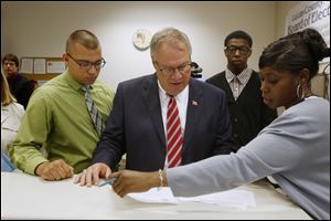 D. Michael Collins, center, goes over paperwork with campaign finance clerk Glynis Fuentes, right, after turning in petition signatures to the Lucas County Board of Elections today.