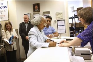 Theresa Gabriel signs paperwork after turning in petition signatures to the Lucas County Board of Elections today. Gabriel is running for Toledo City Council.