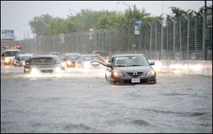 A woman gets back in her car in flood water on Lakeshore West during a storm in Toronto today.