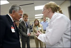 Owens-Illinois research scientist Sara Floyd shows a piece of glass to, from left, U.S. Rep. Bob Latta (R., Bowling Green), Christine Sager, her husband, Swiss Ambassador Manuel Sager, and Marcia Latta, wife of Representative Latta. In the background is Alan Lotozynski, research and development lab manager.