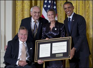 President Barack Obama, right, with former President George H. W. Bush, left, present the 5,000th Daily Point of Light Award to Floyd Hammer and Kathy Hamilton, center, from Union, Iowa, in the East Room of the White House on Monday in Washington.