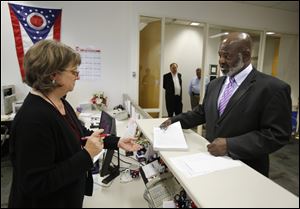 Incumbent Mayor Mike Bell hands petitions to Lori Jacek as files to run for reelection at the Lucas County Board of Elections in Toledo last week.