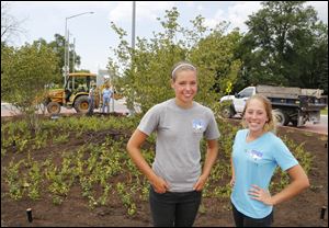 Sarah Parker, left,  and Casey Fuleky replanted the area of land on the roundabout at Brint and Mitchaw Road in Sylvania Township with low-growing junipers, dwarf grasses, groundcover, and trees.