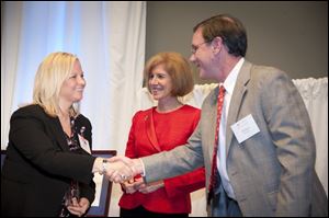 Courtesy photo Lisa Beins McCaig, left, shakes hands with Shaun Gilmore, President of Biomedical Services, as Gail McGovern, President and CEO of the American Red Cross looks on. Mrs. McCaig of Temperance recently received the Presidential Award of Excellence, the highest internal honor presented annually by the American Red Cross. Tonight she joined the Bedford School Board  