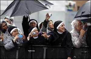 Nuns wave at and takes pictures of Pope Francis as he drives by in his popemobile as he leaves Aparecida, Brazil, Wednesday, July 24, 2013. Tens of thousands of faithful flocked to the tiny town of Aparecida, tucked into an agricultural region halfway between Rio de Janeiro and Sao Paulo, where he is celebrated the first public Mass of his trip in a massive basilica dedicated to the nation's patron saint.  (AP Photo/Victor R. Caivano)