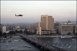 A military helicopter flies over protesters walking on a bridge leading to Tahrir Square today in Cairo.