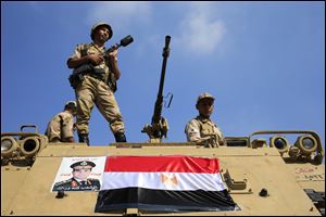 Egyptian soldiers stand guard atop an armored personnel vehicle on a bridge that leads to Tahrir Square in Cairo, Egypt, today.