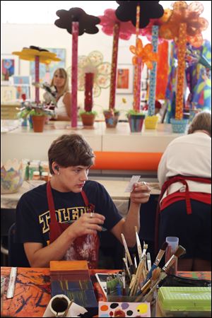 Corey Hawkins selects materials as he works on a painting of the University of Toledo's bell tower. The nonprofit studio both employs and gives classes on fine art to adults with developmental disabilities.