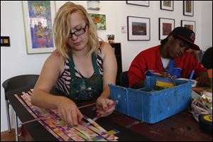 Shanna Richie, left, works on creating a weaving with pieces of canvas and Plexiglass glass as Marc Arnett works on a sky line of New York City during an art session at the Shared Lives Studio in downtown Toledo. 