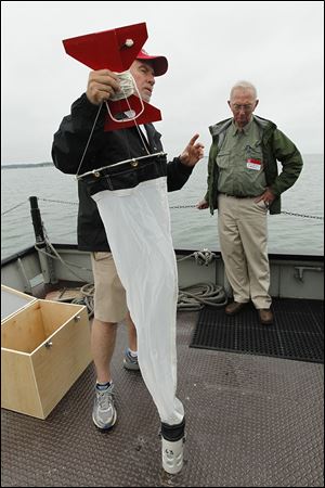 Jeff Reutter, director of the Ohio Sea Grant and Stone Laboratory, demonstrates how to collect zoo plankton in Lake Erie at Stone Laboratory on Put-in-Bay as Dave Baker of Heidelberg University's National Center for Water Quality Research watches.