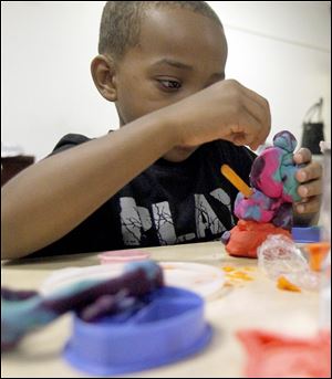 Camarr Burton, 6, concentrates on a clay sculpture at  Ebenezer Missionary Baptist Church. 