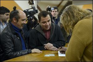 Rodrigo Borda, left, and his partner Sergio Miranda watch a Civil Registry worker take down their information to apply to get married today in Montevideo, Uruguay.