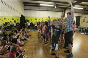 Youngsters aged 10 through 16 perform 'Do You Hear the People Sing?' from Les Miserables for the 6 through 9-year-old fellow actors, seated at left. 