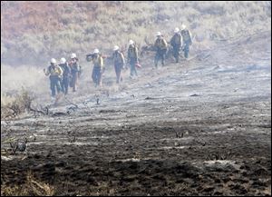 A team of hotshots walk along a fire line near homes on Croy Road and the Rotorun ski hill west of Hailey Idaho today.