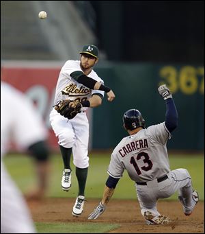 Oakland Athletics second baseman Eric Sogard, left, throws over Cleveland Indians' Asdrubal Cabrera to complete a double play in the second inning.