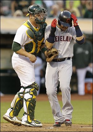 Cleveland Indians' Nick Swisher, right, scores past Oakland Athletics catcher Stephen Vogt in the third inning.