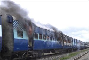 Coaches of the Rajya Rani Express train burn after a mob set it on fire as it ran over a group of Hindu pilgrims at a crowded station in Dhamara Ghat, Bihar state, India, today.