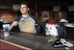 Bowling Green resident Alek Walker sits with his dog Beamer at a bar inside Fifth Third Field.