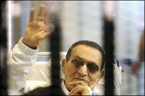 Former Egyptian President Hosni Mubarak waves to his supporters from behind bars in April.